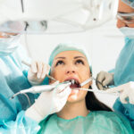 Stomatologist and her assistant treating woman for dental cavity